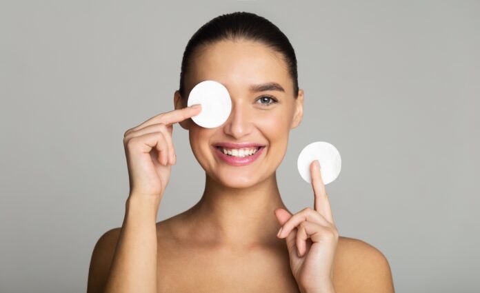 Skin Care. Girl Removing Makeup with Cotton Pads, Having Fun on Grey Background